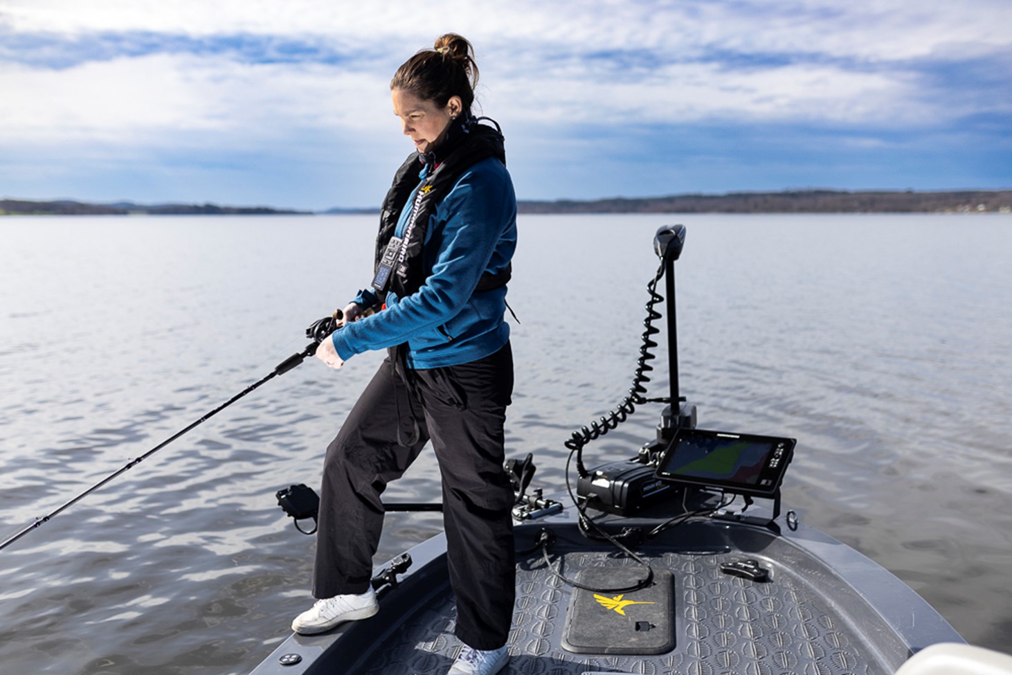 Kvinna står och fiskar från sportfiskebåt utrustad med elmotor och ekolod.